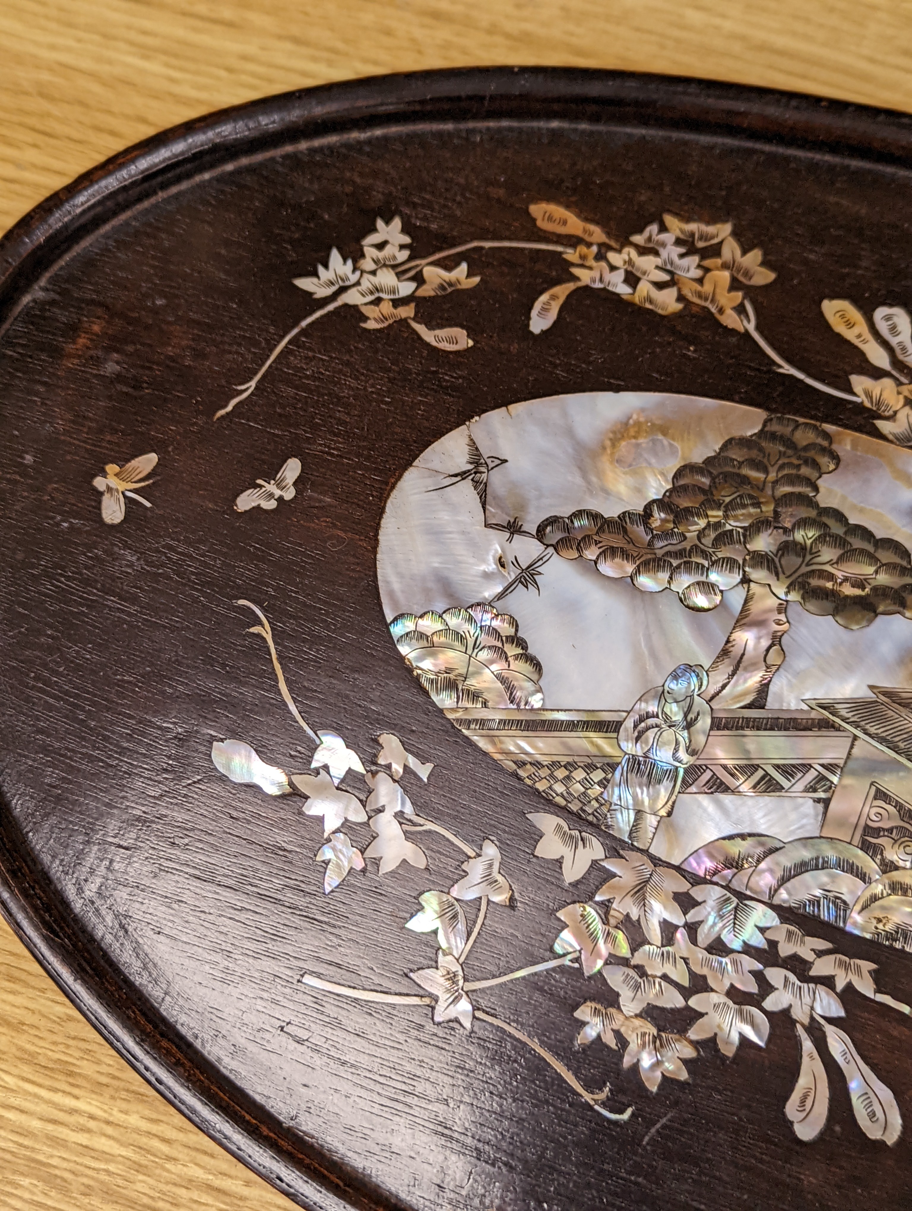Two Chinese mother of pearl inlaid hongmu trays, the rectangular example with birds and insects amid flowers and the smaller oval example with a pavilion in a landscape within floral sprays 55x34cm